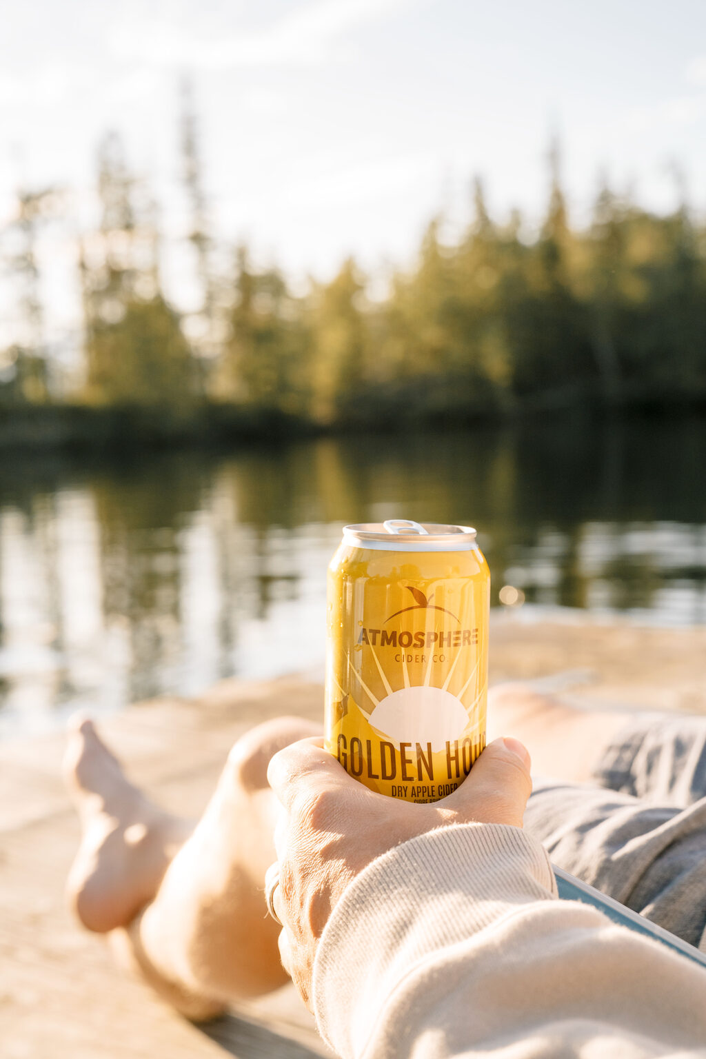 Holding a can of Golden Hour on the dock by the lake
